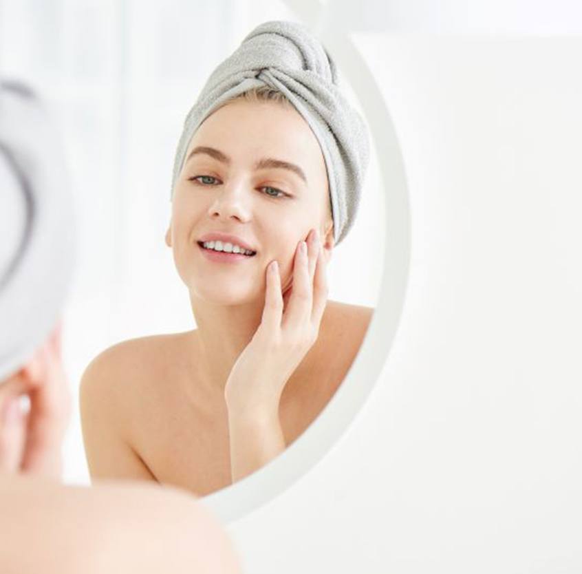Woman with beautiful skin standing in front of mirror