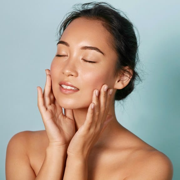 Woman applying skin care products around her jaw line