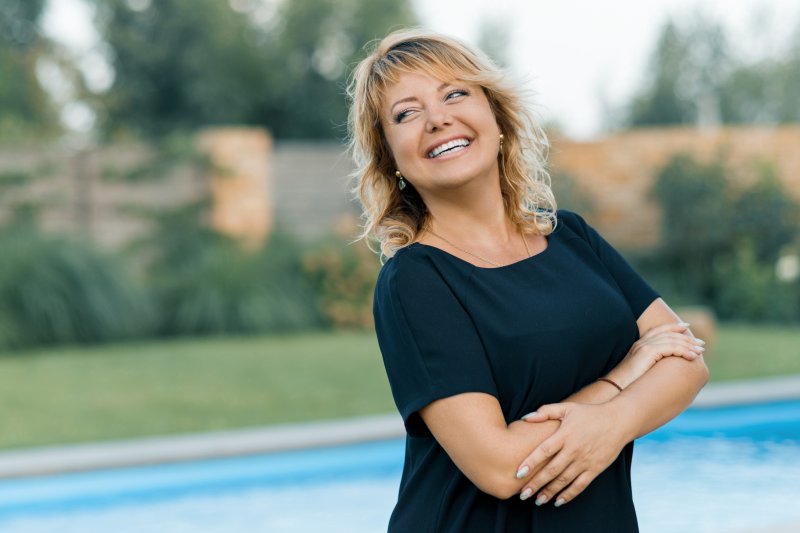 a middle-aged woman smiling while standing outside near her pool
